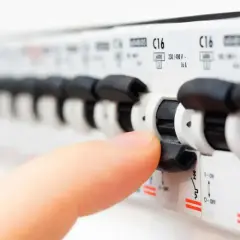 Dłoń wyłącza bezpiecznik. Zastanawiasz się, jaki bezpiecznik do klimatyzacji 5kW będzie najlepszy?