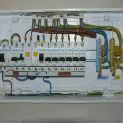 Instalacja elektryczna z bezpiecznikami B16. Widoczne wyłączniki nadprądowe, RCD, listwy zaciskowe N i PE.