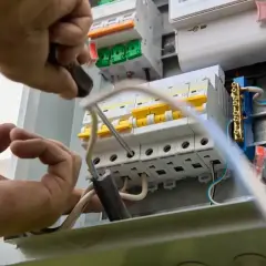 Elektryk montuje bezpieczniki w skrzynce, dobierając odpowiednie jakie bezpieczniki do mieszkania w bloku.