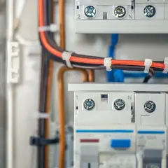 W skrzynce elektrycznej widać uporządkowane bruzdowanie pod kable. Pomarańczowe i brązowe przewody są schludnie spięte opaskami.