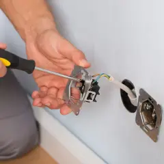 Elektryk dokonuje mostkowania gniazdka z bolcem, przykręcając mechanizm.