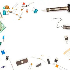 Płytka drukowana, lutownica, cewka, rezystory, kondensatory i inne elementy elektroniczne, w tym warystor, czekają na montaż.