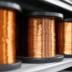 Szpule z miedzianym drutem, gotowe do użycia w instalacjach elektrycznych, gdzie jego wysoka konduktywność jest kluczowa.