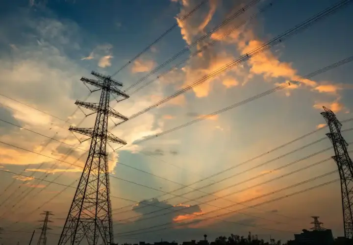 Wieże energetyczne na tle zachodzącego słońca, z chmurami w odcieniach pomarańczy i błękitu. THD.
