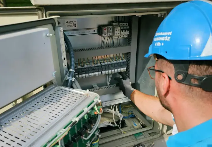 Elektryk pracuje przy panelu sterowania, przygotowując oświadczenie o gotowości instalacji przyłączanej.