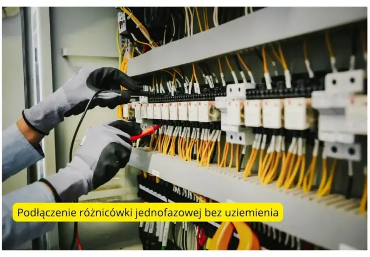 Ręce w rękawicach testujące instalację elektryczną z żółtymi przewodami.