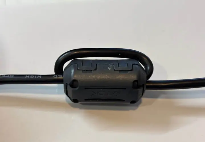 Czarny kabel z nawiniętym na niego ferrytem TDK.