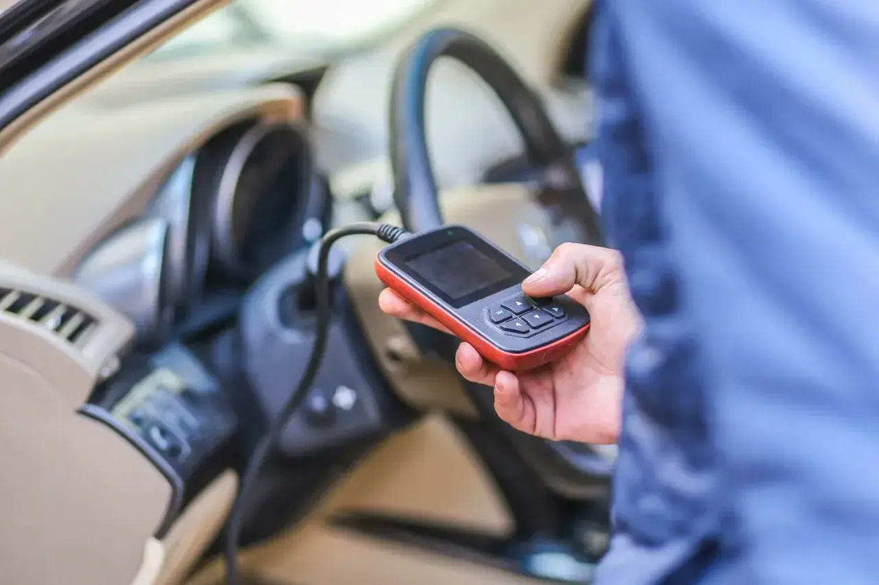 Diagnostyka Renault: ręka trzyma skaner OBD, sprawdzając błędy, np. DTC B1267.
