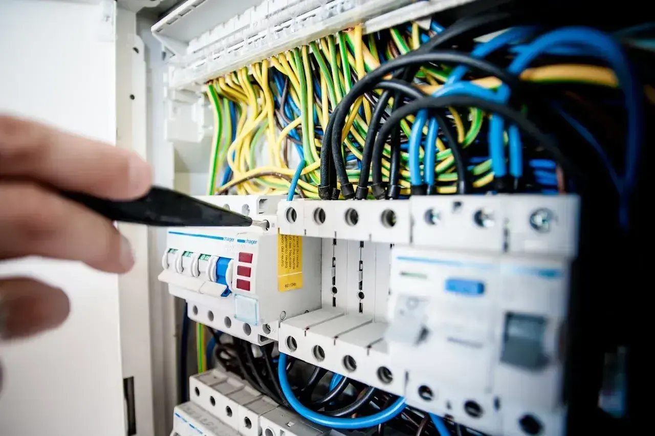 Elektryk sprawdza bezpieczniki w rozdzielnicy. Zastanawiasz się, jaki bezpiecznik do lodówki będzie najlepszy?