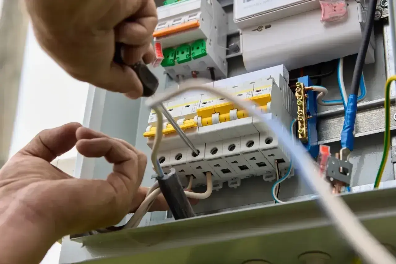 Elektryk montuje bezpieczniki w skrzynce, dobierając odpowiednie jakie bezpieczniki do mieszkania w bloku.