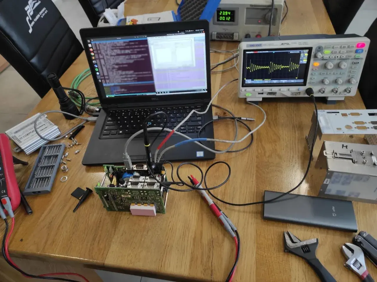 Testowanie układu elektronicznego z użyciem oscyloskopu i laptopa. Widoczne są różne etapy pracy, od podłączenia po analizę sygnału, co pokazuje kolejność faz testowania.