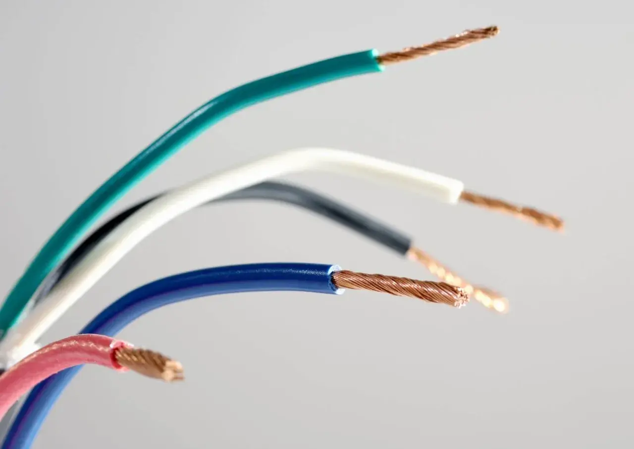 Kilka kolorowych przewodów elektrycznych, w tym zielony, biały, czarny, niebieski i czerwony. Widoczne są miedziane żyły. Jeden z przewodów to przewód neutralny.