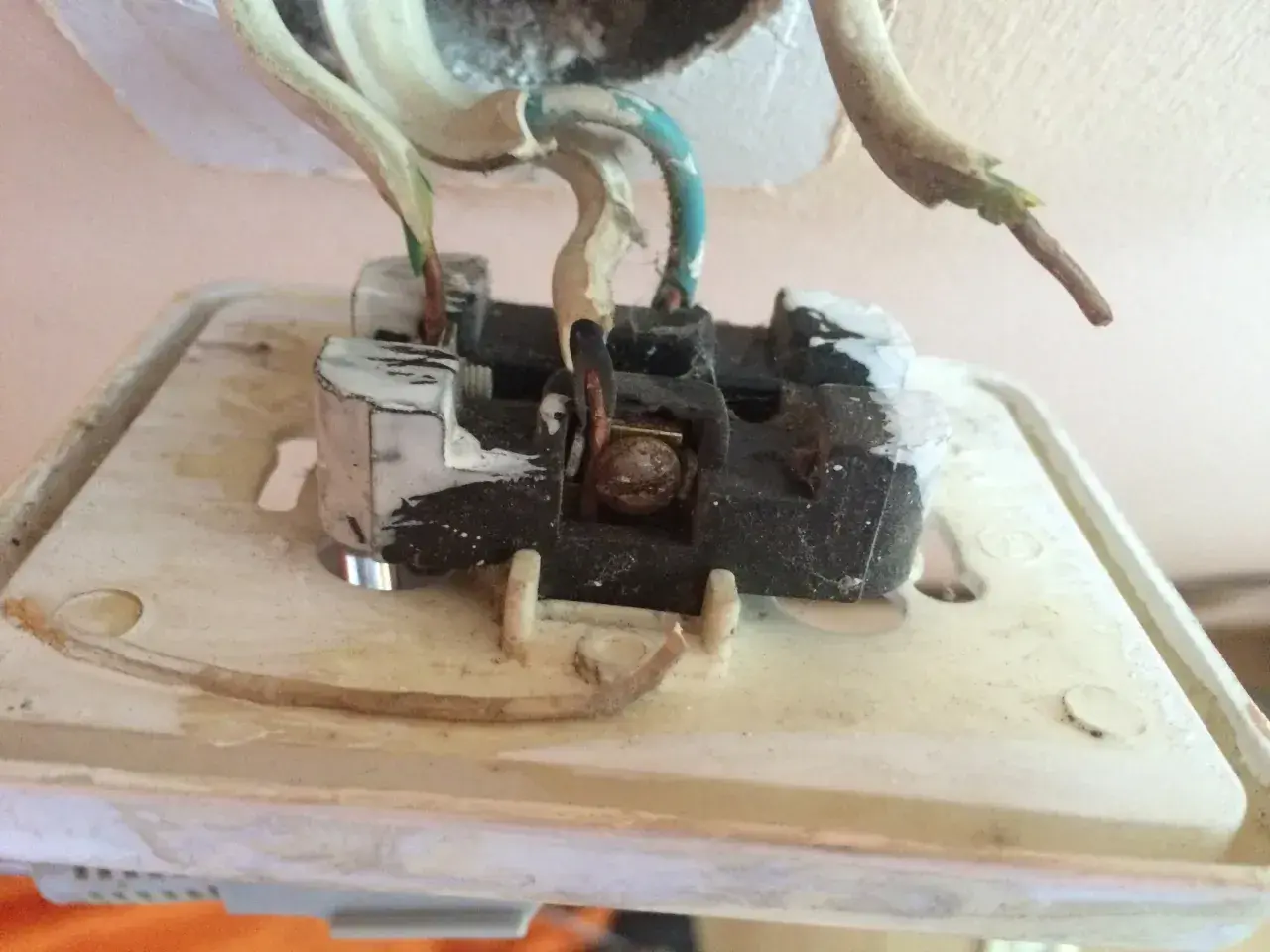 Widok wnętrza gniazdka elektrycznego, pokazujący przewody. Dowiedz się, jak sprawdzić uziemienie w gniazdku miernikiem.