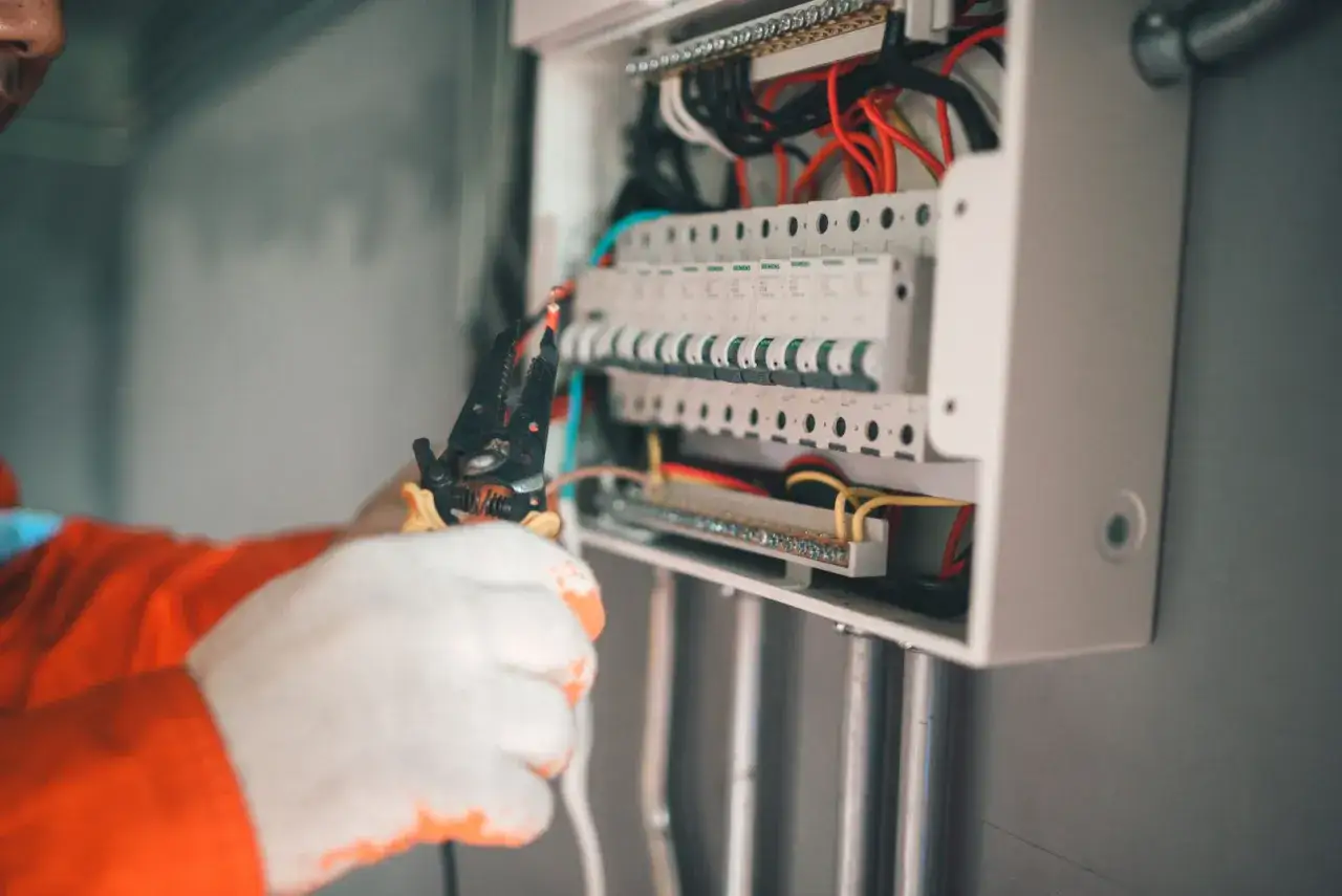 Elektryk pracuje przy skrzynce z bezpiecznikami. Czy bezpiecznik automatyczny może się zepsuć? Tak, jak każdy element elektryczny, może ulec awarii.