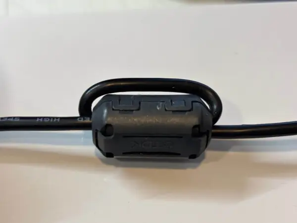 Czarny kabel z nawiniętym na niego ferrytem TDK.